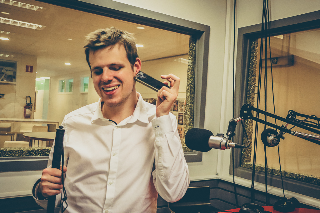 Afbeelding van Anthony Reyers in een radio studio met witte stok in de hand en telefoon aan het oor.