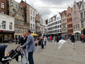 A street in Antwerp full of people and a sculpture on the ground